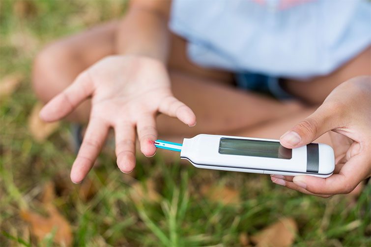 Kind macht Blutzuckertest bei Diabetes