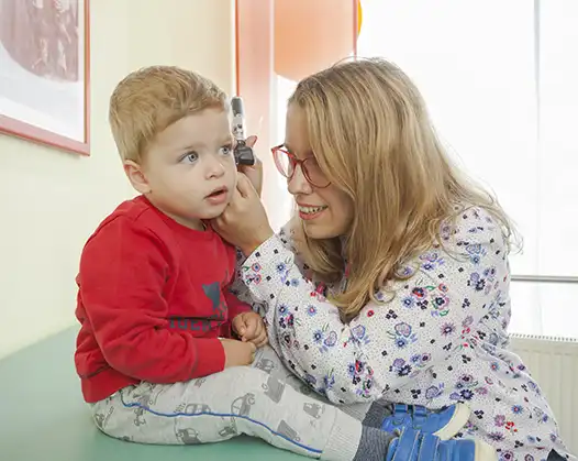 Kinderärztin Frau Diamanti untersucht Kleinkind mit Ohrenspiegel